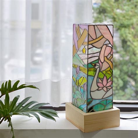 A Stained Glass Lamp Sitting On Top Of A Window Sill Next To A Potted Plant