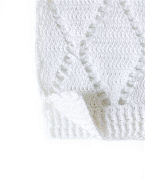 A White Knitted Blanket Laying On Top Of A Table