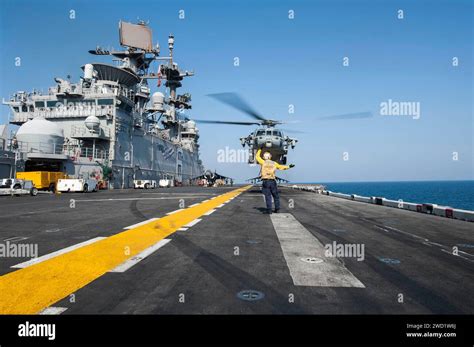 Aviation Boatswain S Mate Signals An MH 60S Sea Hawk Helicopter To Lift