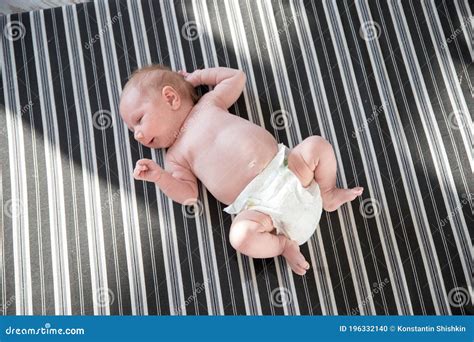 Cute Newborn Baby In A White Diaper Lying On A Bed Stock Photo Image