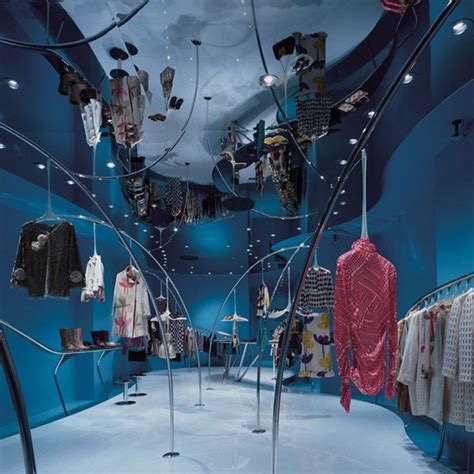 the inside of a clothing store with blue walls and clothes hanging on ...