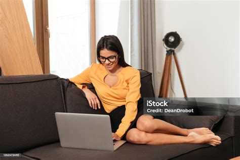 Woman In Eyeglasses Working With Laptop While Sitting On Couch Stock