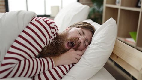 Young Redhead Man Lying On Bed Hugging Teddy Bear At Bedroom Stock