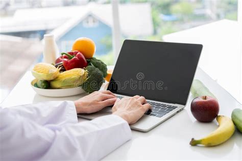 Portrait Of Asian Smiling Female Nutritionist Typing On Laptop Computer