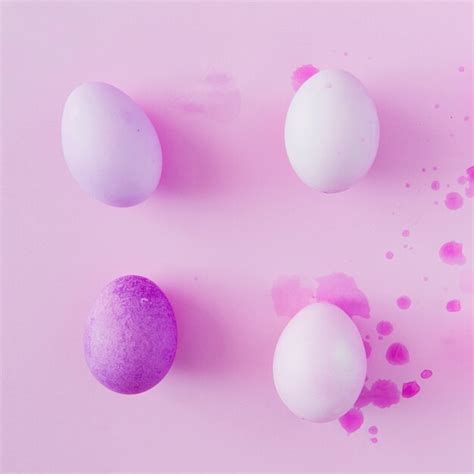 Huevos de pascua violetas y blancos entre salpicaduras de tinte líquido