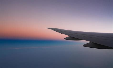 Wing Of Plane With Beautiful Sunrise Skyline Airplane Flying On Blue