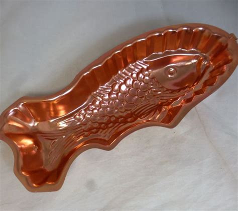 A Metal Fish Shaped Dish On A White Surface