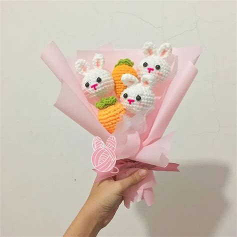 A Hand Holding A Bunch Of Small Crocheted Carrots And Rabbits On Top Of