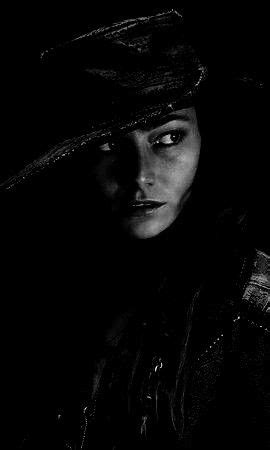 A Black And White Photo Of A Woman In The Dark With A Hat On Her Head