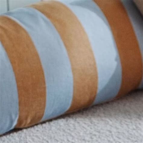 A Close Up Of A Blue And Brown Striped Pillow On The Floor Next To A Bed