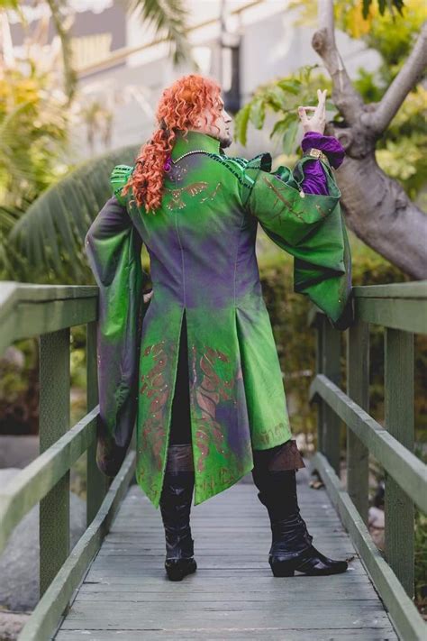 A Man Dressed In Green And Purple Is Standing On A Bridge