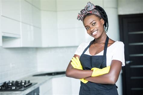 Smiling African American Housewife In Apron With Arms Crossed Cleaning