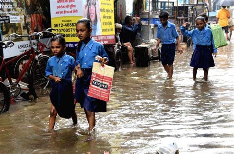 School Students Wade Through A Waterlogged Street After Heavy Rainfall