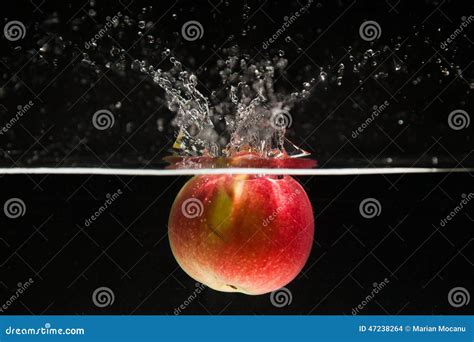 Red Apple Falling Into The Water With A Splash Royalty Free Stock Image