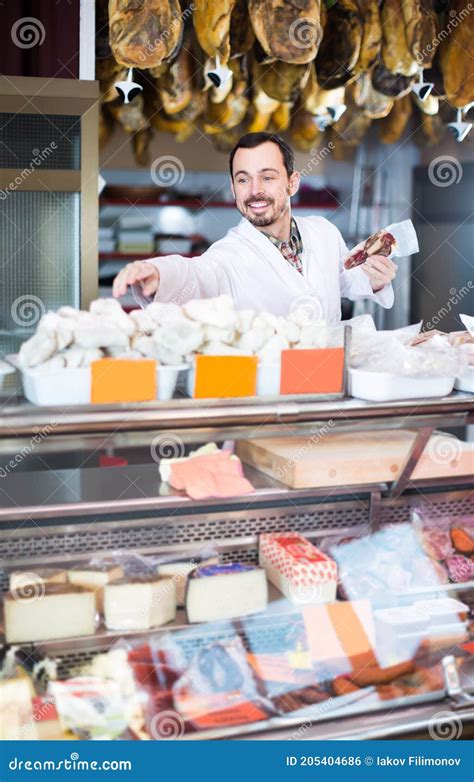 Polite Male Shop Assistant Demonstrating Sorts Of Meat In Shop Stock