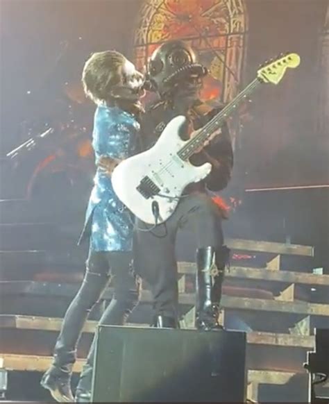 Two People Standing On Stage With Guitars In Their Hands