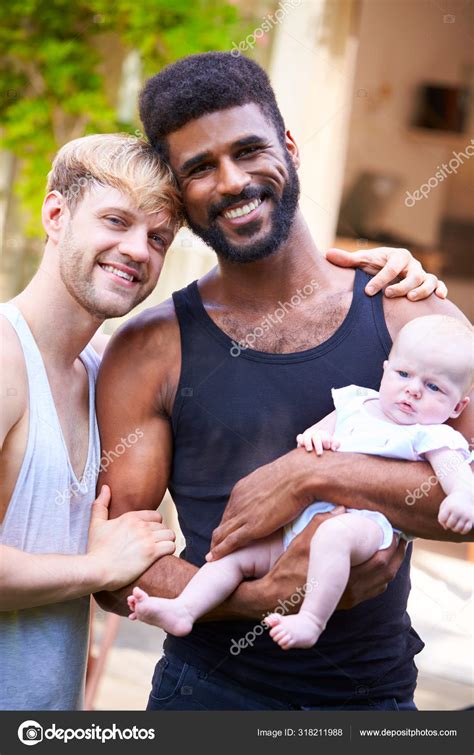 Portrait Loving Male Same Sex Couple Cuddling Baby Daughter Home