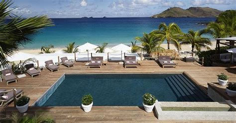 An Outdoor Swimming Pool With Lounge Chairs And Umbrellas On The Beach