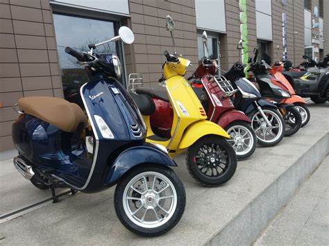 Several Scooters Are Lined Up On The Side Of The Street In Front Of A