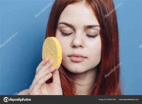 Cute Redhead Woman Naked Shoulders Wipes Face With Sponge Skin Care