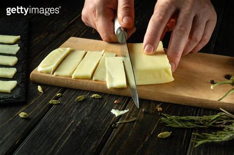 Close Up Of A Man Hands Using A Knife To Cut Mozzarella Cheese Into