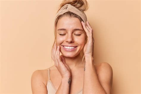 Free Photo Photo Of Pleased Young European Woman Keeps Eyes Closed Touches Face Gently Has