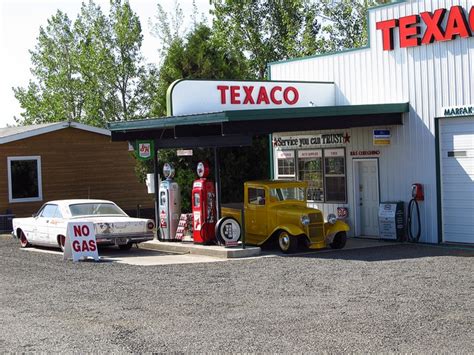 An Old Yellow Truck Parked In Front Of A Texaco Gas Station