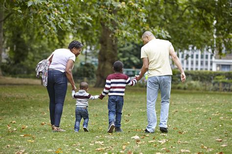 Mum, Dad and children walking in park - First4Adoption