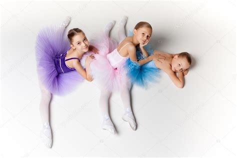 Tres pequeñas chicas de ballet sentadas en tutú y posando juntas ...