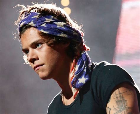 A Man With A Bandana On His Head Is Looking Off To The Side While Standing In Front Of A Stage