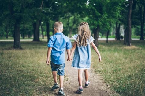 Um Menino E Uma Menina Caminhando Juntos E De M Os Dadas Foto Premium