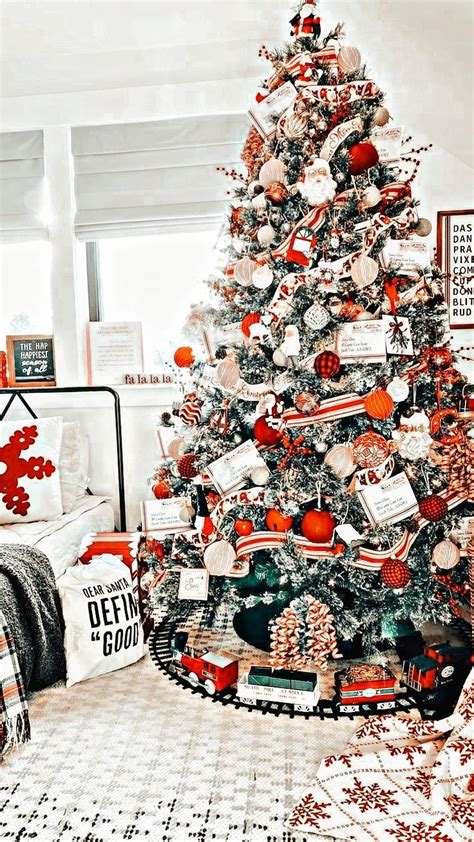 a decorated christmas tree in a living room with red and white ornaments on the top