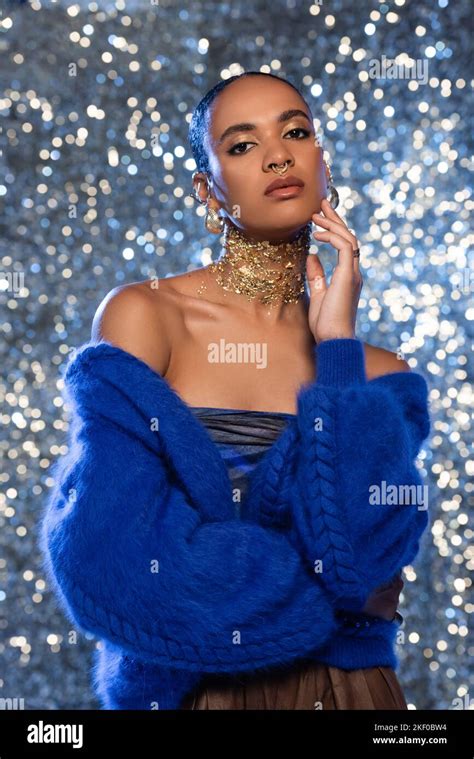 Stylish African American Model In Jacket And Accessories Touching Face On Sparkling Background