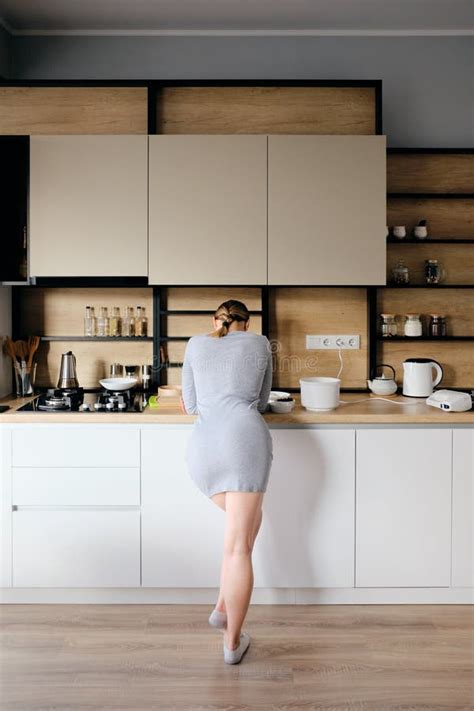 Back View Of Woman Standing Next To A Modern Kitchen Stock Image