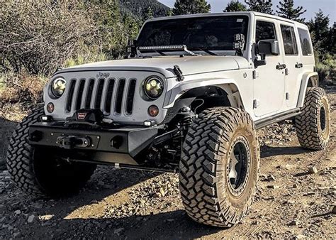 A White Jeep Driving Down A Dirt Road