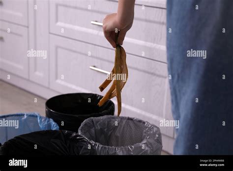 Woman Throwing Banana Peel Into Trash Bin In Kitchen Closeup Separate