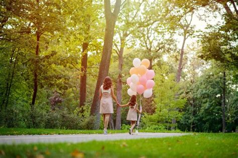 Mom And Daughter Holding Hands Walk In The Summer In The Park With A