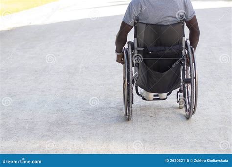 Back View Of Black Man In Wheelchair Riding Along Wide Road Stock Image