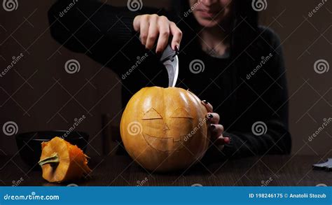 Young Brunette Woman Carves A Pumpkin For Halloween Preparation Stock