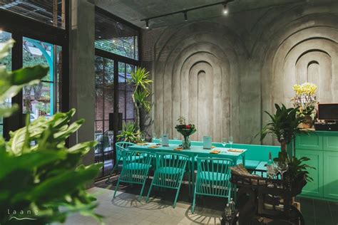 A Restaurant With Green Tables And Chairs In Front Of An Arched Wall