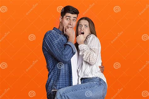 Scared Millennial Guy And Lady Cover Their Mouths With Hands And Look