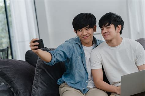 Romántica pareja gay joven selfie divertido por teléfono celular en casa asiático amante