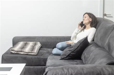 Relaxed Brunette Talking On Cellphone While Sitting On Sofa Stock Image