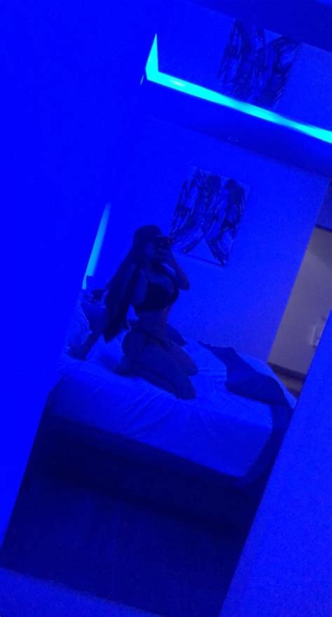 A Person Sitting On A Bed In A Room With Blue Lights