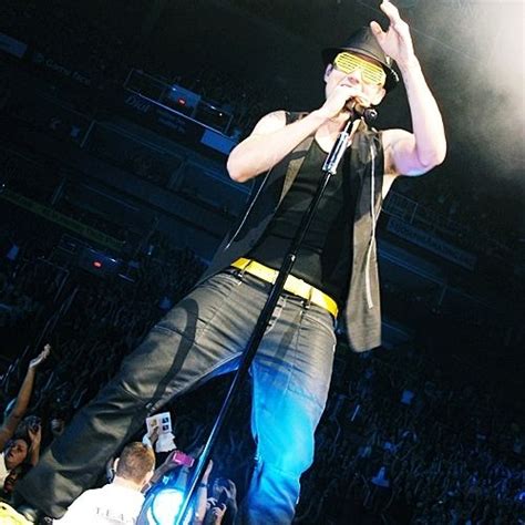 a man standing on top of a stage with his hands up in the air as he sings