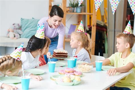 Blonde Mignonne Petite Fille Soufflant Des Bougies Sur Le Gâteau D anniversaire Par Table Servie