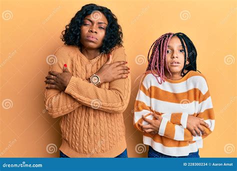 Beautiful African American Mother And Daughter Wearing Wool Winter Sweater Shaking And Freezing