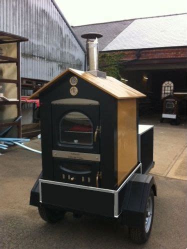 An Outdoor Wood Burning Oven Sitting On The Back Of A Cart In Front Of