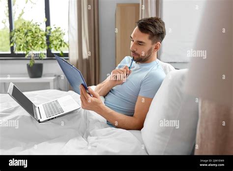 Man With Laptop Working In Bed At Home Bedroom Stock Photo Alamy