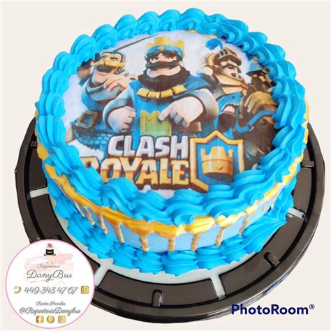 A Cake With Blue Frosting And Gold Trimmings That Says Clash Royale On It